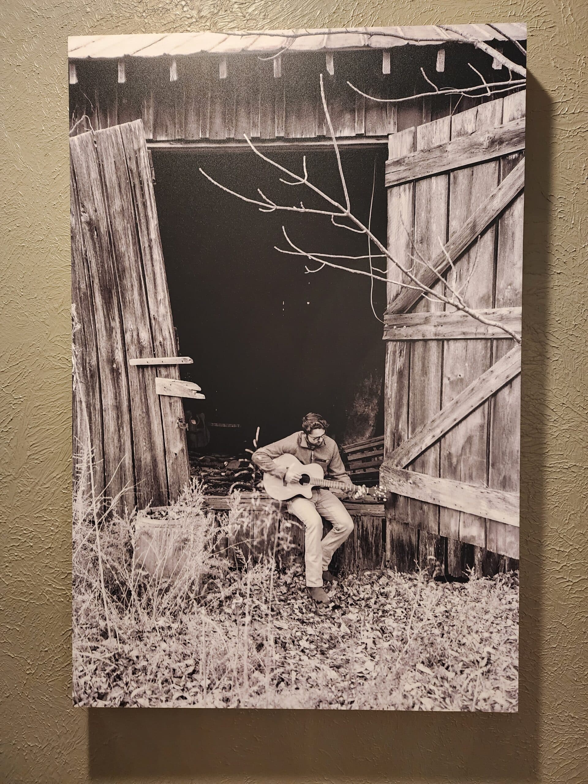 young man playing guitar in the doorway of an old barn young man playing guitar in the doorway of an old barn
