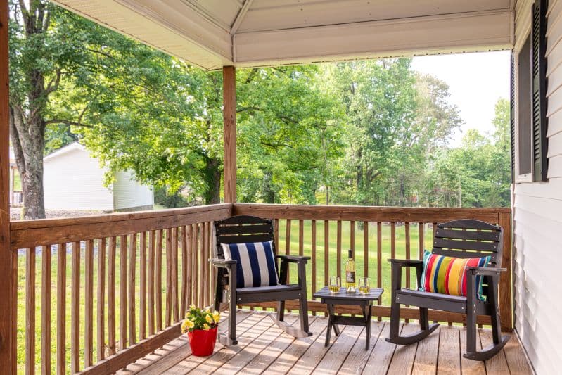 front porch with two black chairs and a side table